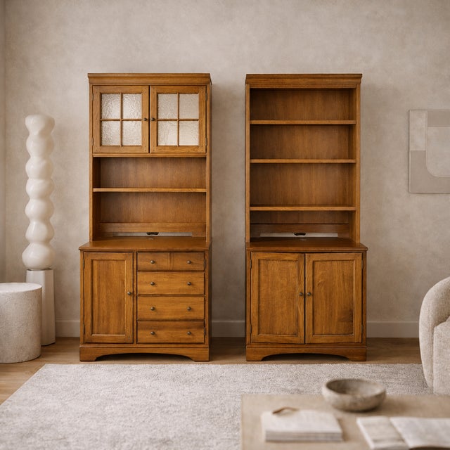 Pair of cottage style oak hutch cabinets with glass doors, lower storage, and warm oak finish. Each cabinet has a tall...