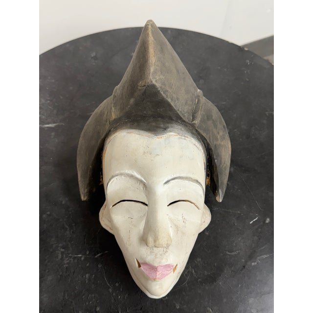 Design Plus Gallery presents an African Punu-Style Carved Wood Mask. Carved from wood, this sculptural mask presents an...