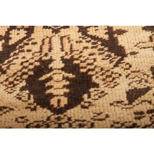 Hand-knotted in wool originating from India circa 1910-1920, this 9x12 antique rug connotes an Agra design in a...