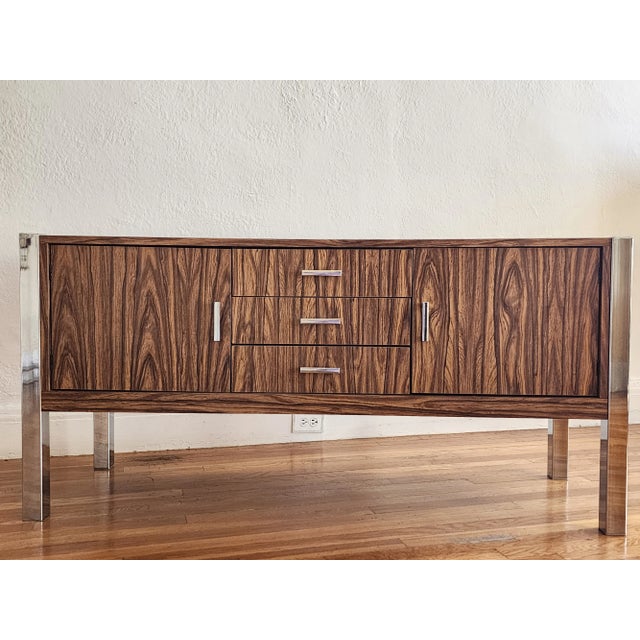 Handsome late 1960's Mid Century Modern credenza featuring a faux rosewood laminated finish with chrome pulls and chrome...