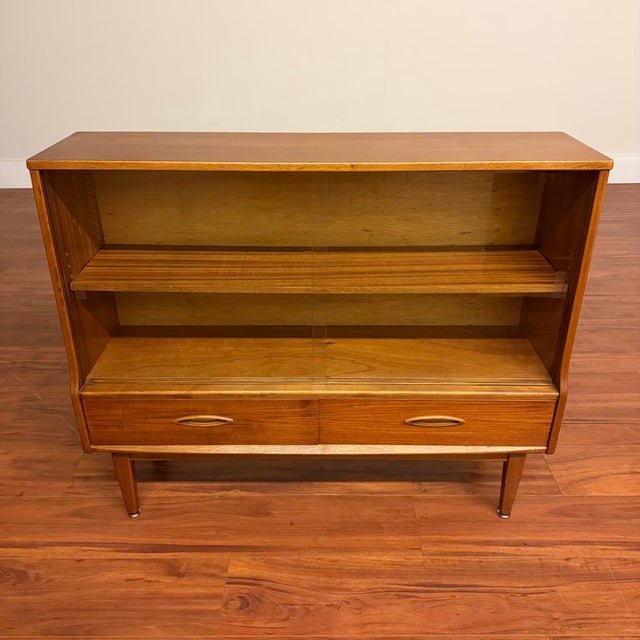 Vintage low bookcase / display case with glass doors and two drawers, made in the U.K. by Jentique circa 1960's. This cute...