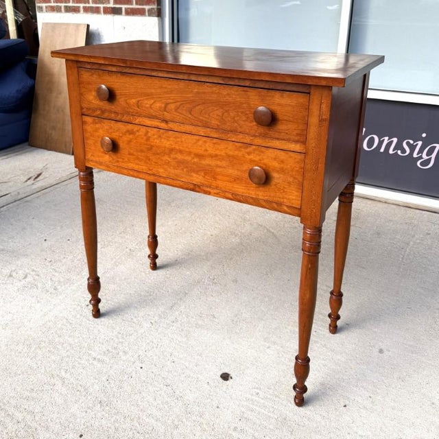 This early 1900s solid cherry two-drawer hunt board features a warm, richly grained surface with a simple rectangular top...