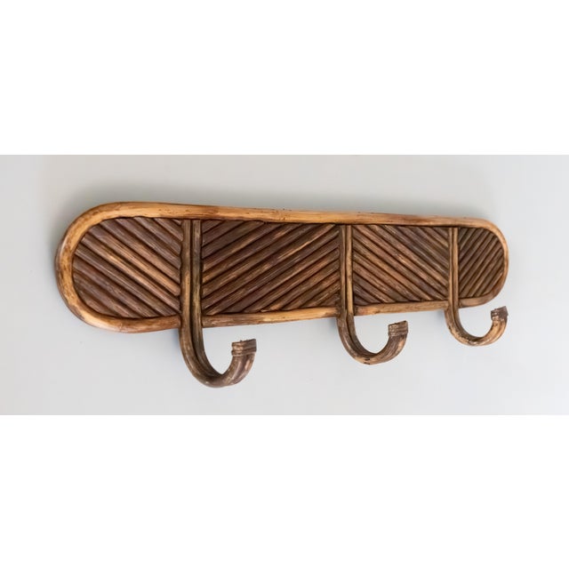 A stylish vintage Italian Crespi style pencil reed bamboo coat rack with three curved hooks. It has a chic design in a...