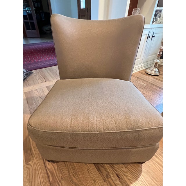This elegant slipper chair has a textured tan fabric upholstery with a subtle crackle pattern. This piece is designed by...