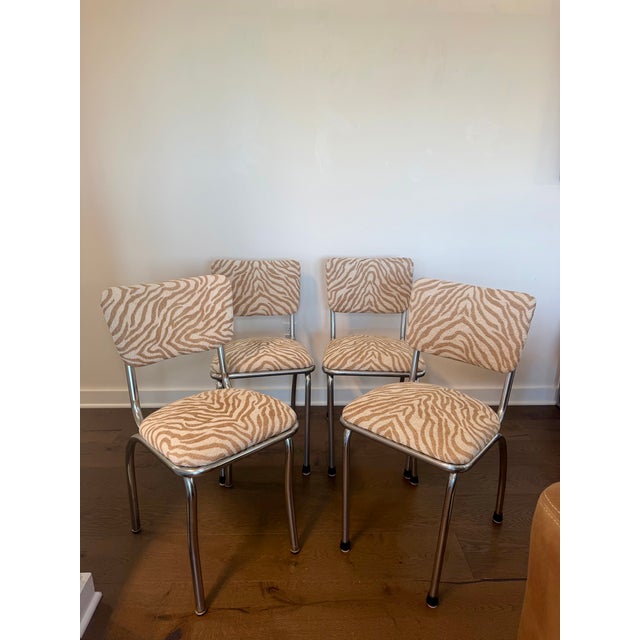 A set of four vintage chrome dinette chairs, newly reupholstered in soft tan and cream tiger-print chenille. The plush...