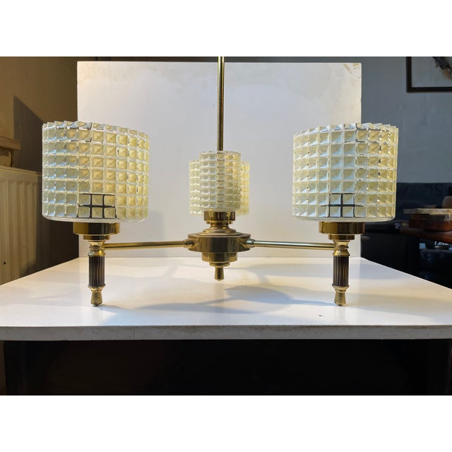 A beautifully crafted 3-shaded hanging lamp with subtle midcentury detailingI. It's made from brass and the 3 shades from...