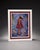 Decorative framed portrait print featuring a young girl in a red dress and hat against a colorful blue, purple, and...