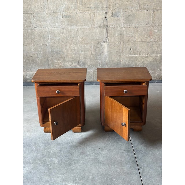 An Art-Deco period pair of nighstands. Dark wood and detailed metal knobs. One large drawer and one large cabinet per stand.