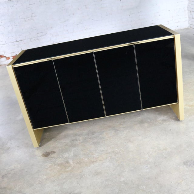 Elegant small credenza or server cabinet attributed to Ello in black glass and gold anodized and brushed aluminum. It is...