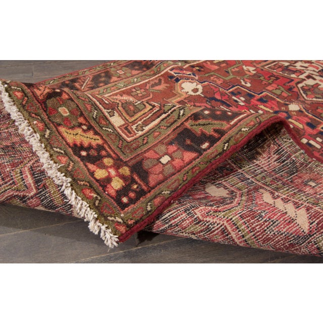 A beautiful Vintage Heriz Handmade Wool Rug with a red field and multicolor accents in allover geometric medallion design....