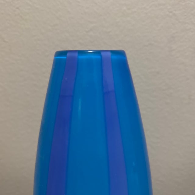 Add a touch of elegance to your space with this beautiful blue glass cylinder vase featuring vertical striped detailing....