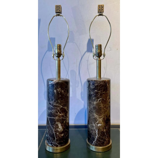 Pair of brass base marble cylindrical form table lamps with finials in the Art Deco fashion. Shades are not included.