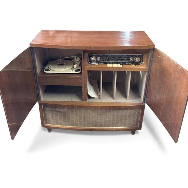 This vintage walnut radiogram from the 1950s is a classic British furniture piece that combines mid century modern design...
