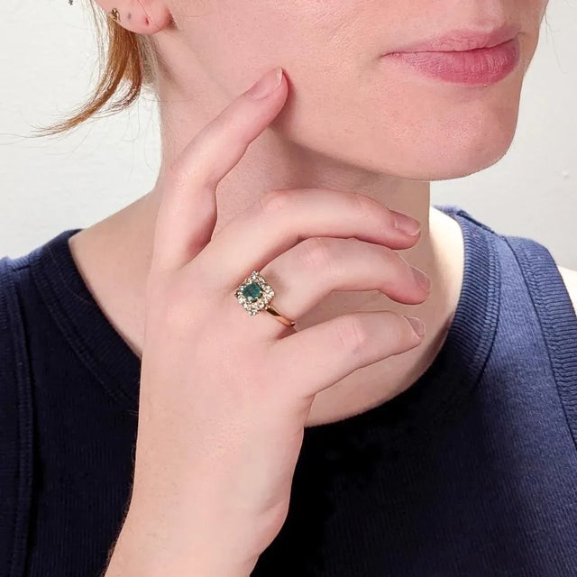 A fine antique gold, emerald, and diamond ring. In 14 karat yellow gold. With a central prong-set 0.55ct± emerald cut...