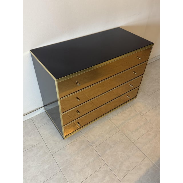 Chest of drawers by Renato Zevi, 1970, in gold mirrored glass and brass. Four drawers. Black glass top. Intact and in good...