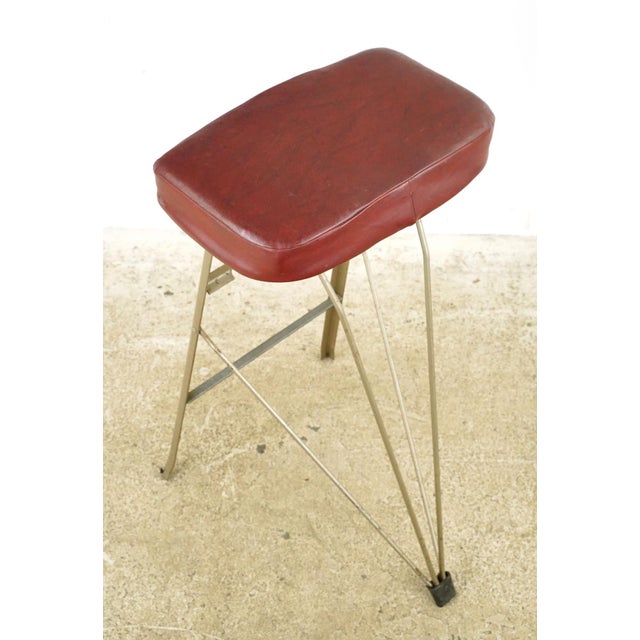 1950s Industrial style folding workshop stool with a steel frame and a red imitation leather seat. Good condition with...