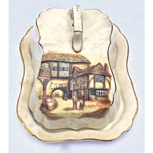 Antique covered cheese dish with underplate and handled lid. Unique scalloped shape with hand-painted Tudor tavern on the...