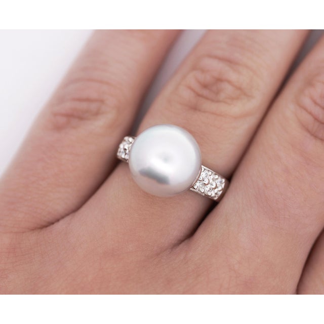 12mm Pearl and Round Cut Diamond Ring in Platinum. The shiny white pearl is bezel set into the traditional style ring...
