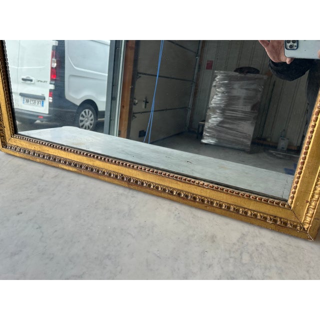 Louis XVI style giltwood mirror, circa 18th century. Adorned with a pediment and frame decorated with pearls and heart-...