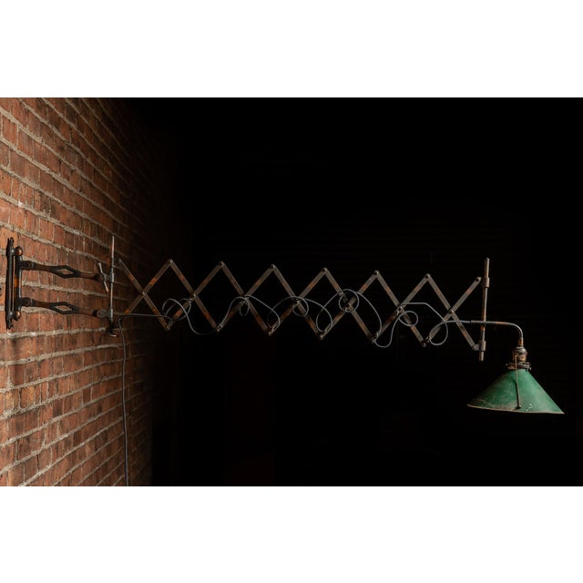 Industrial scissor-arm wall lamp with copper flashing, mirrored green shade, and decorative Art Nouveau vine motif. This...