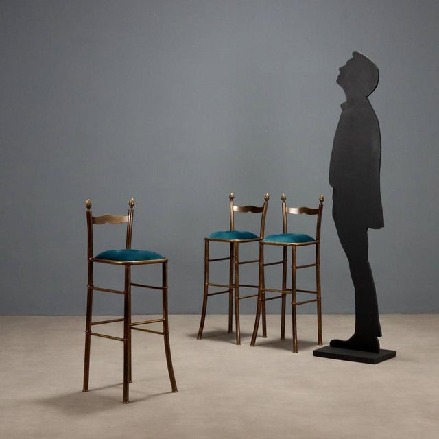 Set of three elegant stools, brass frame with foam seat and velvet upholstery. Restored. This piece is attributed to the...