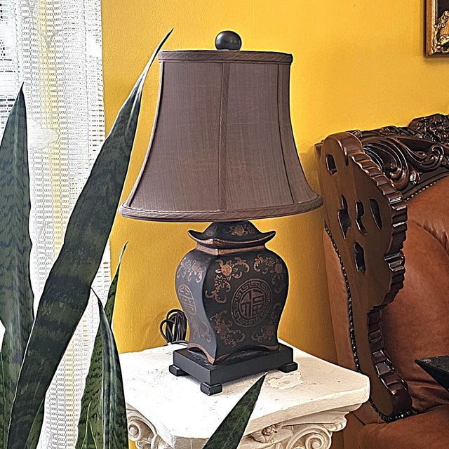 Elegant Asian-inspired porcelain table lamp featuring a black glazed body accented with brown medallion motifs, floral...