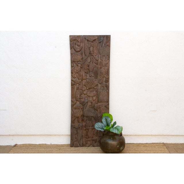 This antique Nupe door from Nigeria is carved across three narrow planks with an asymmetrical program of figures rather...