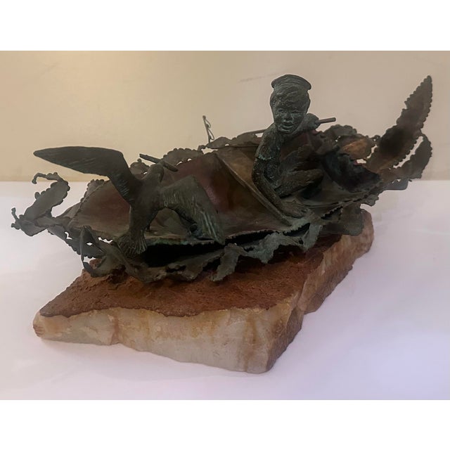 A small figure sitting in a turned position towards the back of the boat. Birds gather close, one with wings lifted mid-...