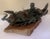 A small figure sitting in a turned position towards the back of the boat. Birds gather close, one with wings lifted mid-...