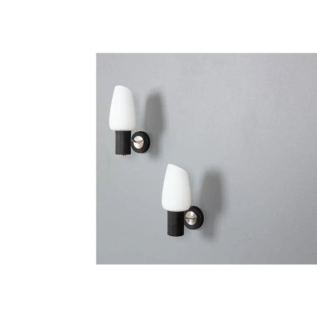 Set of 2 wall lights made by Arlus in the 50s. Metal wall mount, brass vertical arm, white opal glass reflectors. 2 x B22...