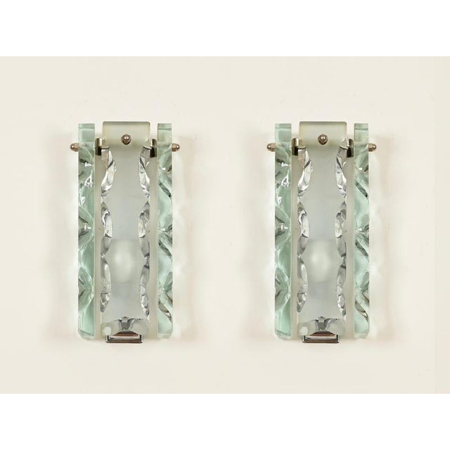 Stunning and unique pair of sculptural sconces in hand-chiseled glass and chromed metal. These incredibly elegant lights...