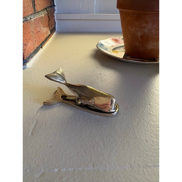 Whimsical vintage brass whale-form clip featuring a sculptural whale body and detailed tail fin that functions as a...