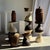 Large hand-woven basket with a slightly flared cylindrical shape resting on a square wooden base. The dense chevron weave...