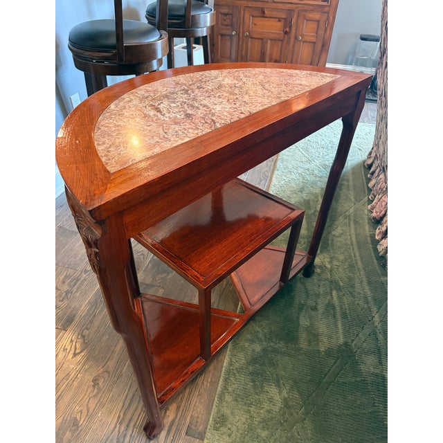 Striking vintage Chinese-style carved hardwood demilune console featuring a beautiful inset marble top. The elegant half...