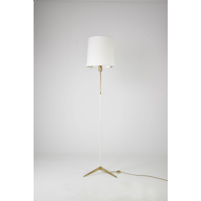 An Italian floor lamp from the 1950s in brass and white lacquered metal, designed in the style of Stilnovo. The lamp is...
