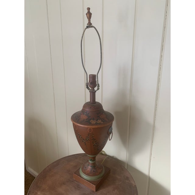 A beautiful vintage Neoclassical style brown tole lamp with hand-painted foliate swag and fruit accents. There are two...
