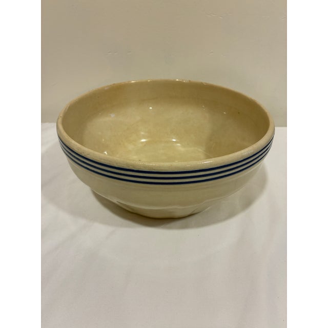Vintage stoneware mixing bowl featuring traditional cobalt blue banded stripes and a warm cream glazed finish. The classic...