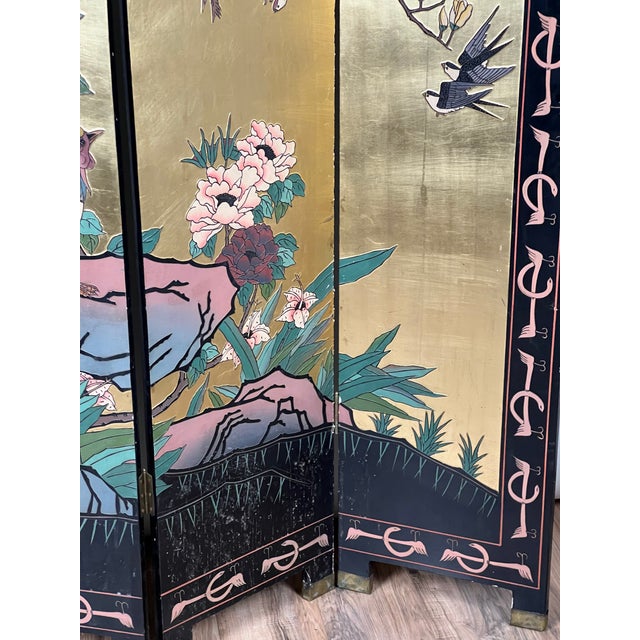This striking vintage Asian Coromandel screen is richly decorated in black lacquer with a luminous gilt ground, featuring...