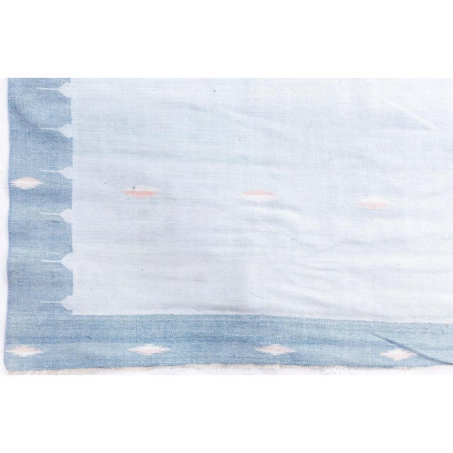 Subtle elegance defines this vintage Indian Dhurrie, handwoven in the mid-20th century with a masterful sense of balance...