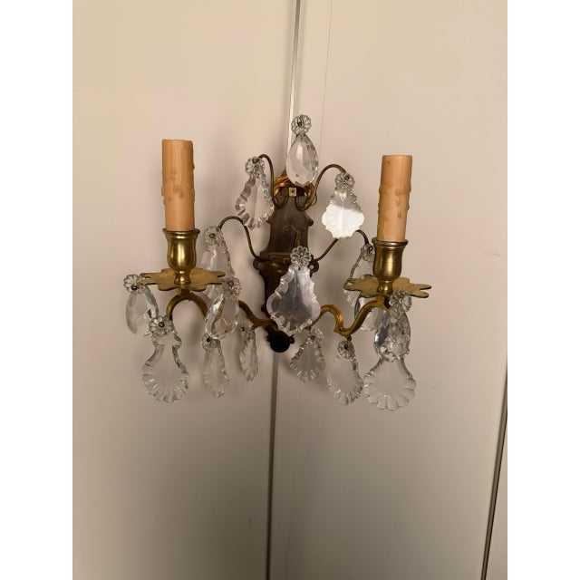 Pair of two-arm French wall sconces dating to circa 1890, crafted in bronze and crystal with elegant decorative detailing....