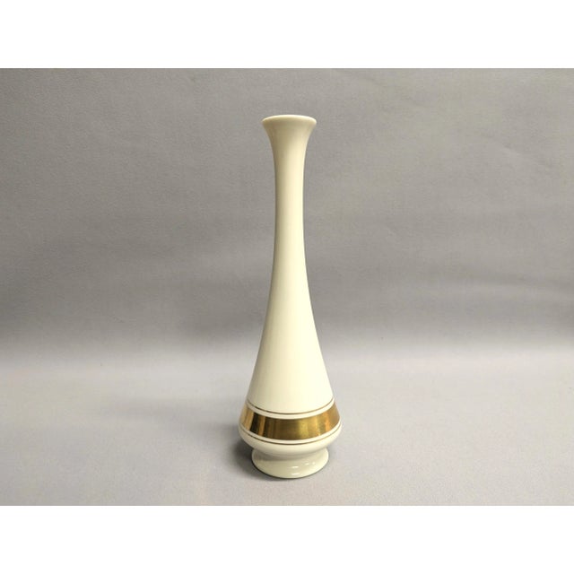 A vintage Lenox bud vase from the Minaret collection. The tall porcelain vase has three gold bands on the lower section. A...