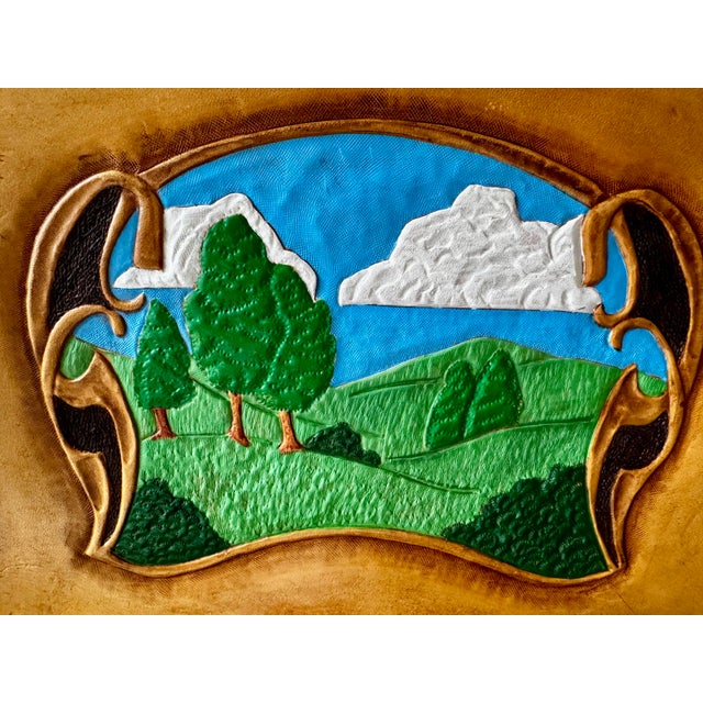 A richly textured vintage hand-tooled leather landscape mounted in a carved wood frame. The dimensional leatherwork is...