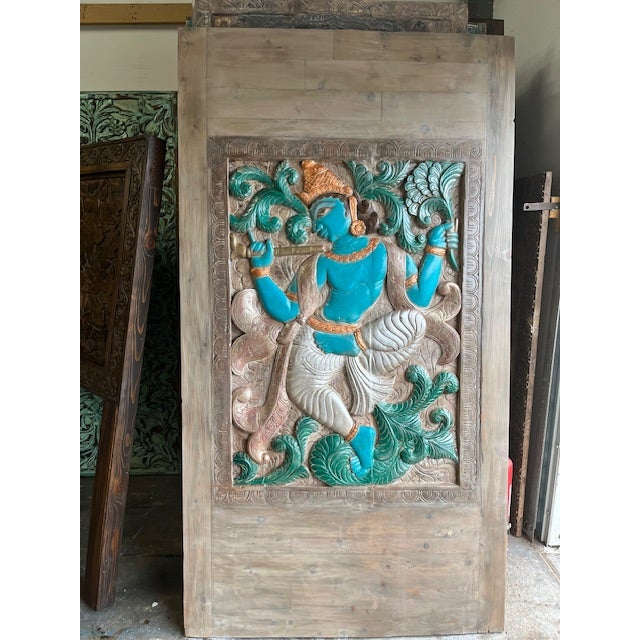 A breathtaking piece of devotional art, this hand-carved wooden panel features a richly detailed depiction of Krishna,...