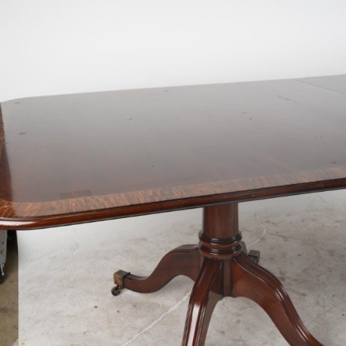 Regency style mahogany dining table by Burton Ching Ltd., San Francisco. This finely crafted table includes two 18-inch...