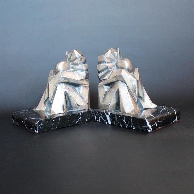 A pair of art deco bookends by fontinelle in the form of stylised, silvered bronze pierrots seated on marble plinths....