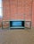Bring a pop of soulful color and rustic utility to your space with this vintage industrial low cabinet. Featuring a...