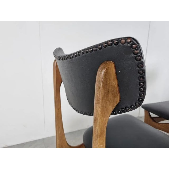 Mid-Century dining chairs designed by Louis van Teeffelen. Beautifully crafted curved teak frames with a black leatherette...