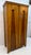Distinctive vintage armoire crafted in warm golden-toned wood, featuring striking contrasting wood panels and beautifully...