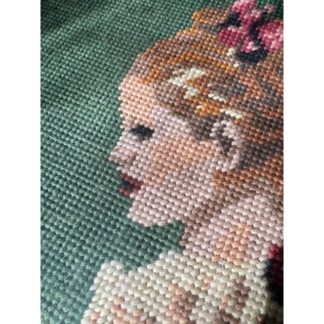 Elegant vintage Danish needlepoint depicting a seated woman reading, rendered in warm rose and golden tones against a deep...