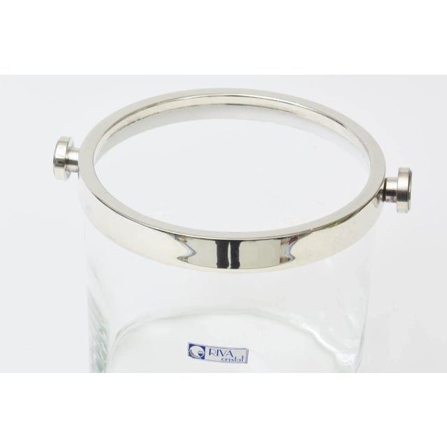 This simple modern looking stickered Riva Crystal glass ice bucket has stainless steel handles that look like silver-...